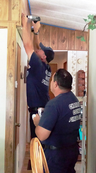 Firefighters installing a smoke detector